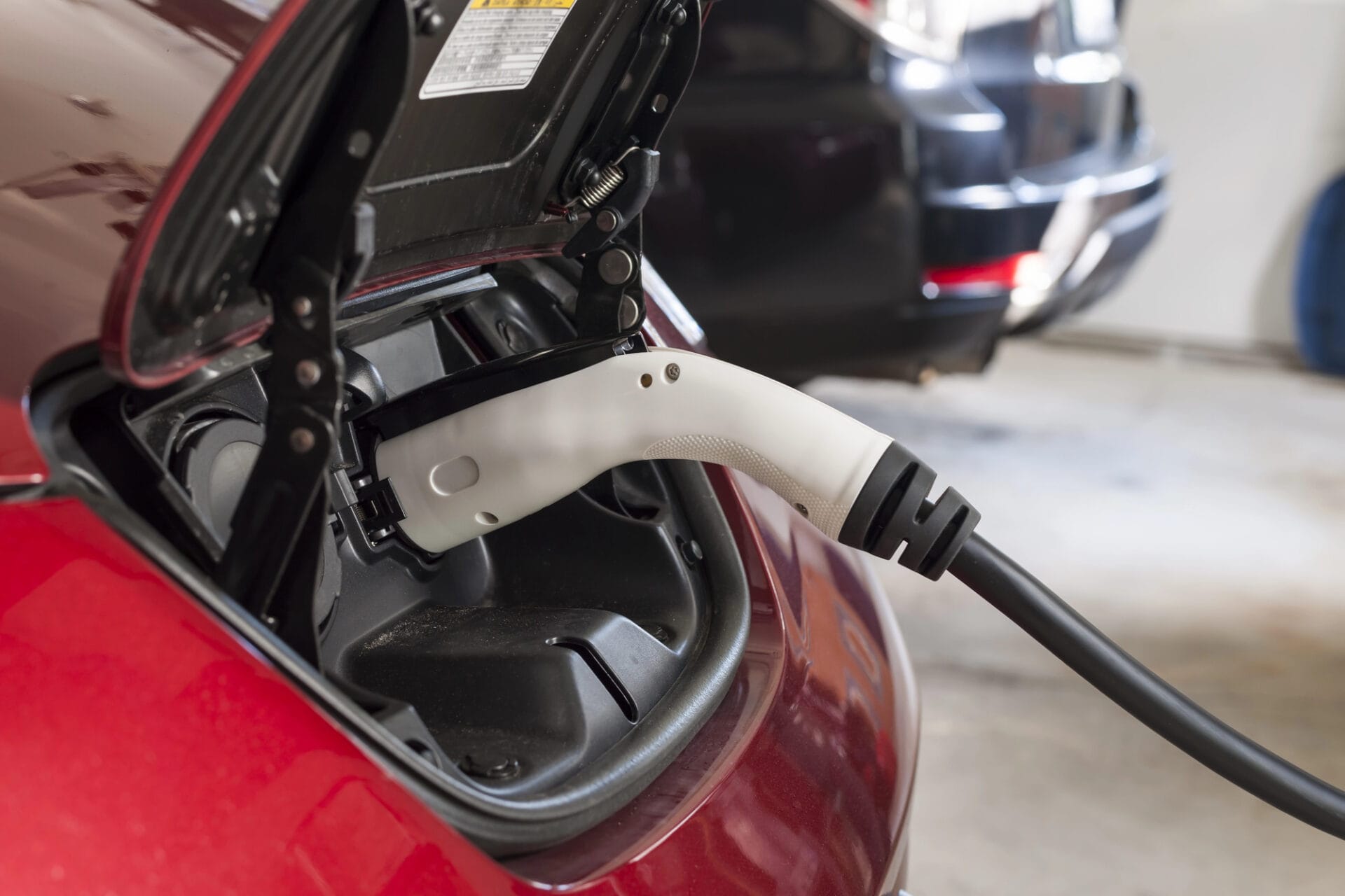 Electric car charging with a plugged-in white charging cable in the garage.